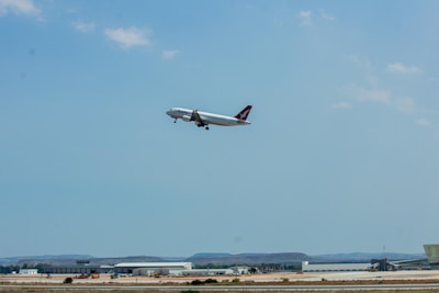 An airplane taking off over a blue sky with a hint of green landscape below.
