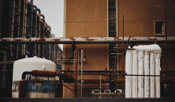 Technicians installing thermal insulation on large industrial pipes at a power plant.