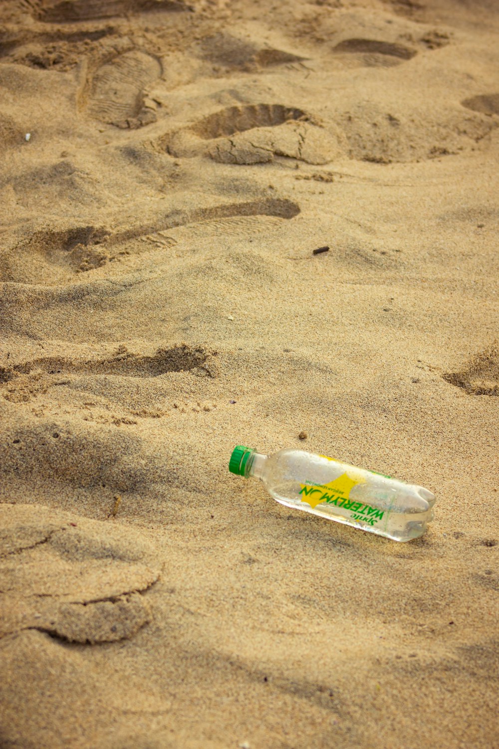 an empty plastic bottle sitting in the sand