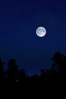 A serene night sky filled with stars and a glowing full moon