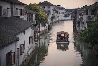 a boat traveling down a river next to a row of houses