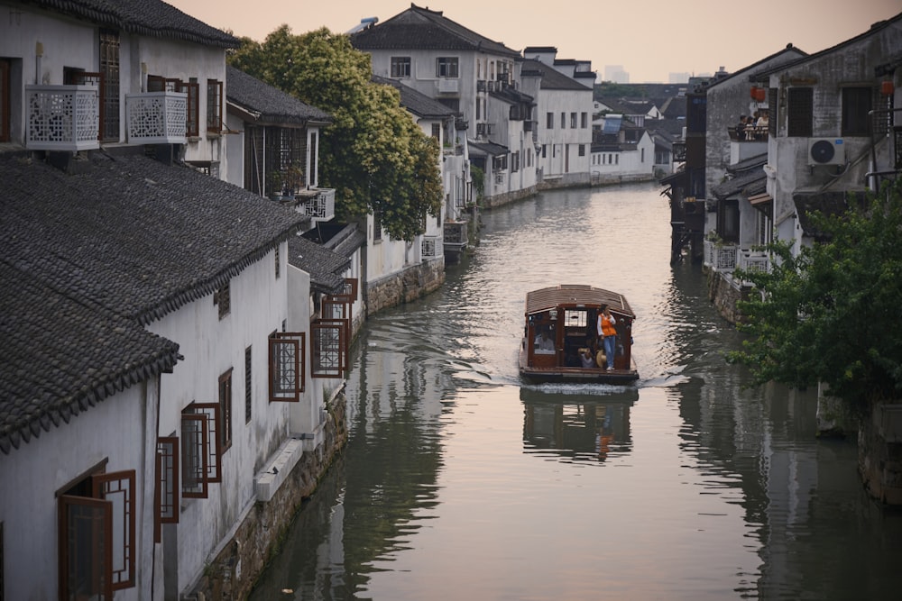 a boat traveling down a river next to a row of houses