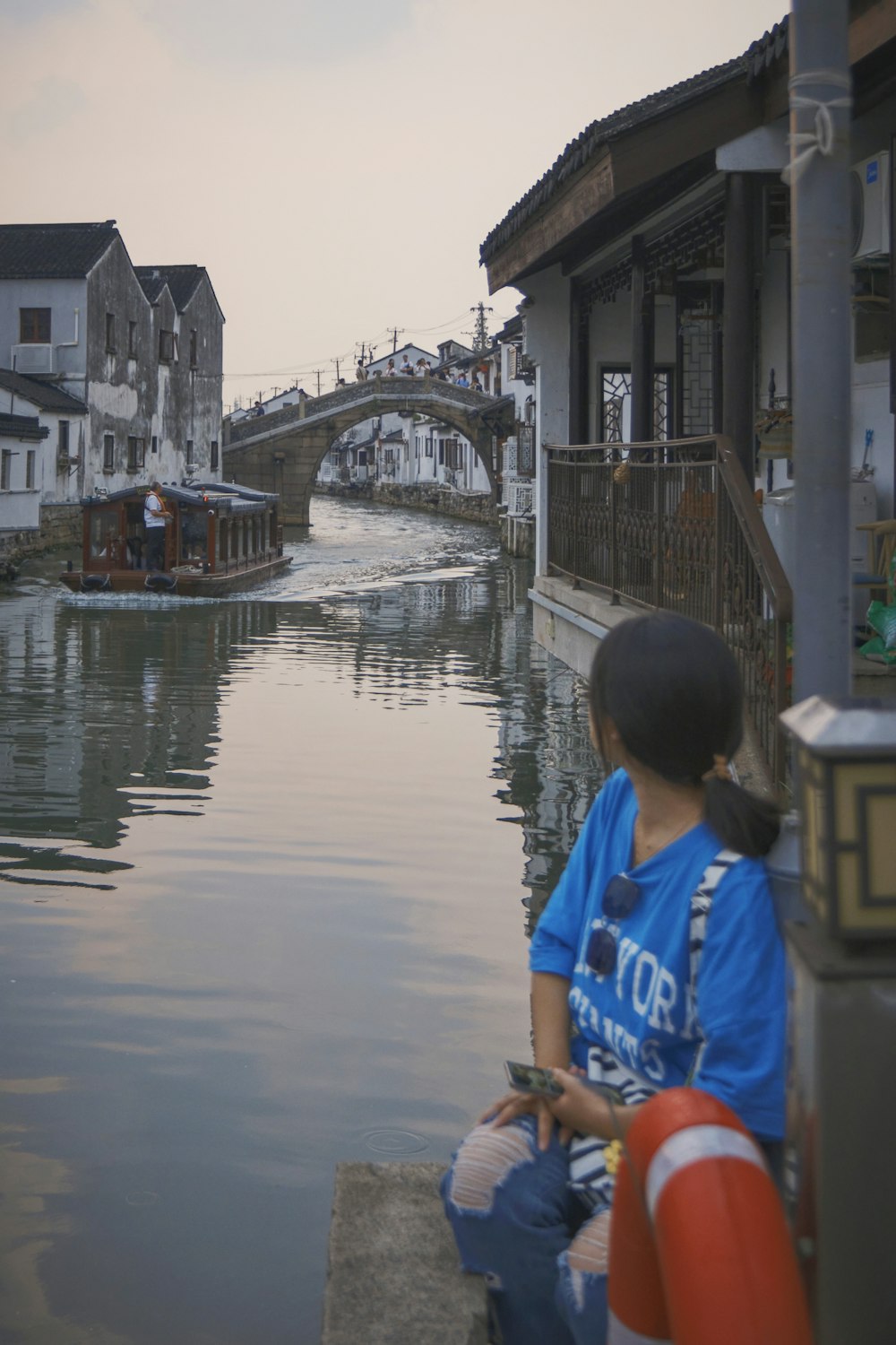 a woman sitting on a ledge looking at the water