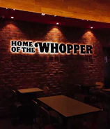 Cozy interior of Burger House with wooden tables, dim lights, and customers enjoying their meals