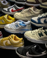 A variety of sneakers are displayed, showcasing different brands and color schemes. Prominent brands featured include Nike and New Balance. The shoes are arranged closely together, highlighting their unique design elements such as logos and color accents.