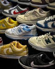 A variety of sneakers are displayed, showcasing different brands and color schemes. Prominent brands featured include Nike and New Balance. The shoes are arranged closely together, highlighting their unique design elements such as logos and color accents.