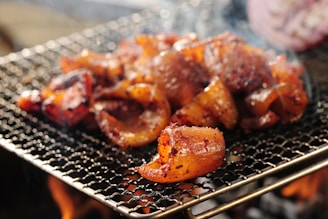 Close-up of sizzling meat on a traditional parrilla grill with smoke rising.