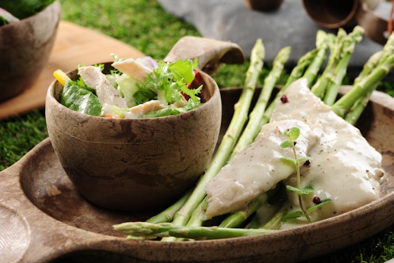 Close-up of fresh chicken liver, vegetables, and grains arranged on a rustic wooden table.
