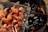 Grilled meat pieces arranged on a wire mesh over glowing charcoal. The meat appears to be well-seasoned and cooked, with a slightly glossy and caramelized finish. The charcoal beneath is dark and partially lit, with visible orange flames.