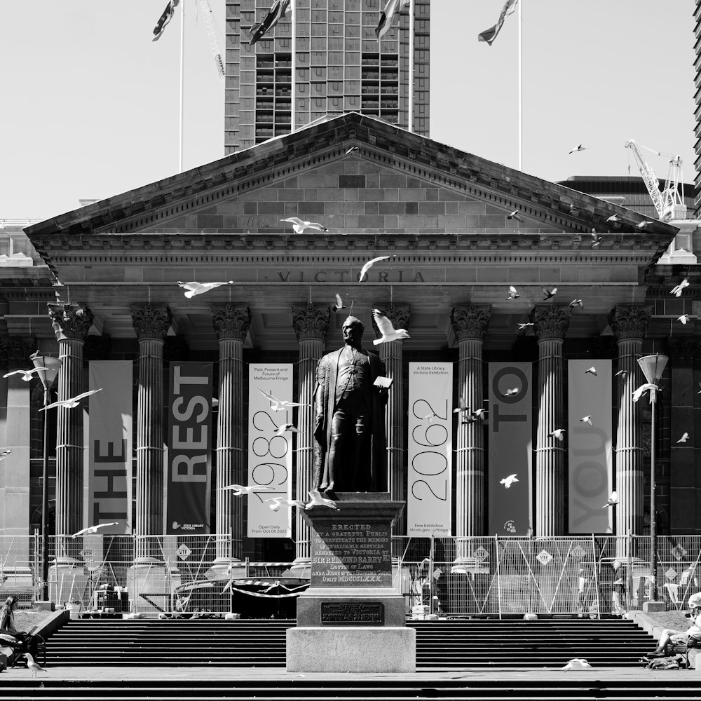 a black and white photo of a statue in front of a building