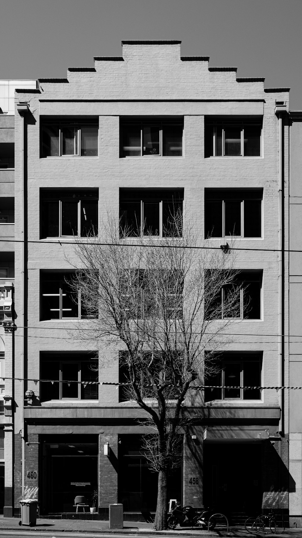 Una foto en blanco y negro de un edificio con un árbol frente a él