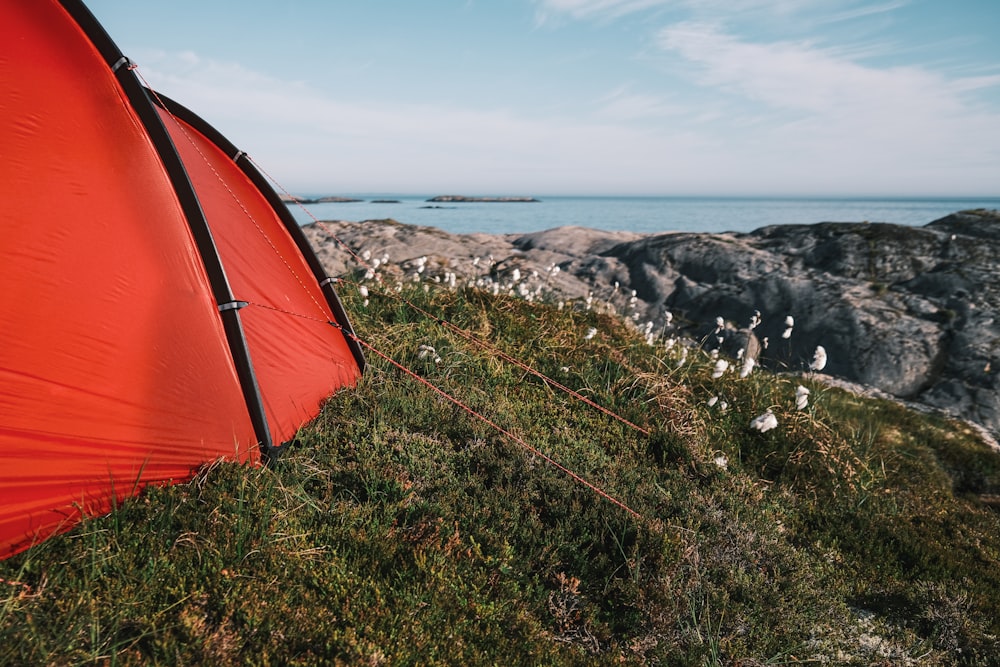 a red tent sitting on top of a lush green hillside