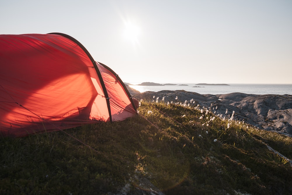 a red tent sitting on top of a lush green field