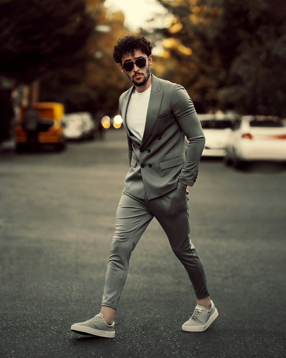 a man in a suit and sunglasses walking across a street