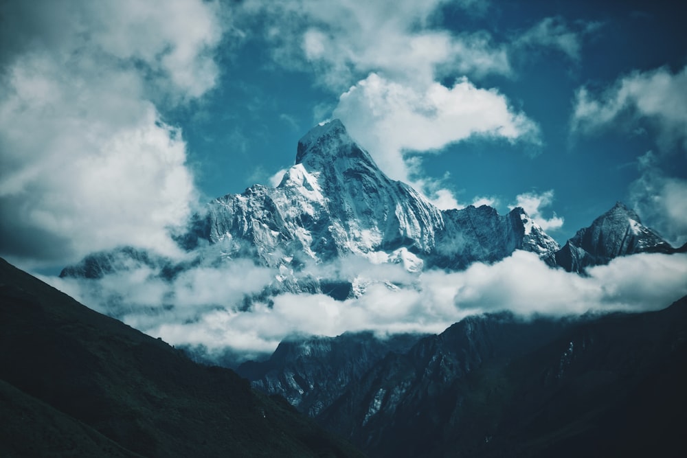 a snow covered mountain in the middle of a cloudy sky