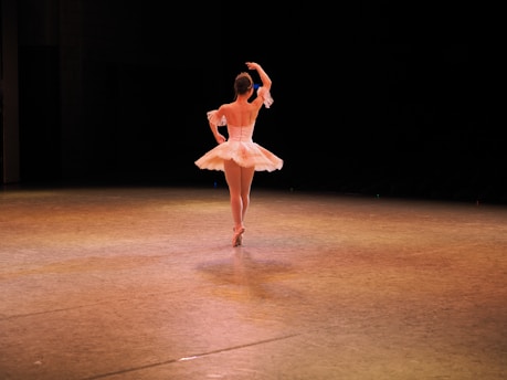 Young ballet dancer practicing on stage in a classical tutu.