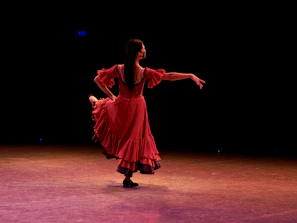 A flamenco dancer in a flowing red dress performing passionately on stage.