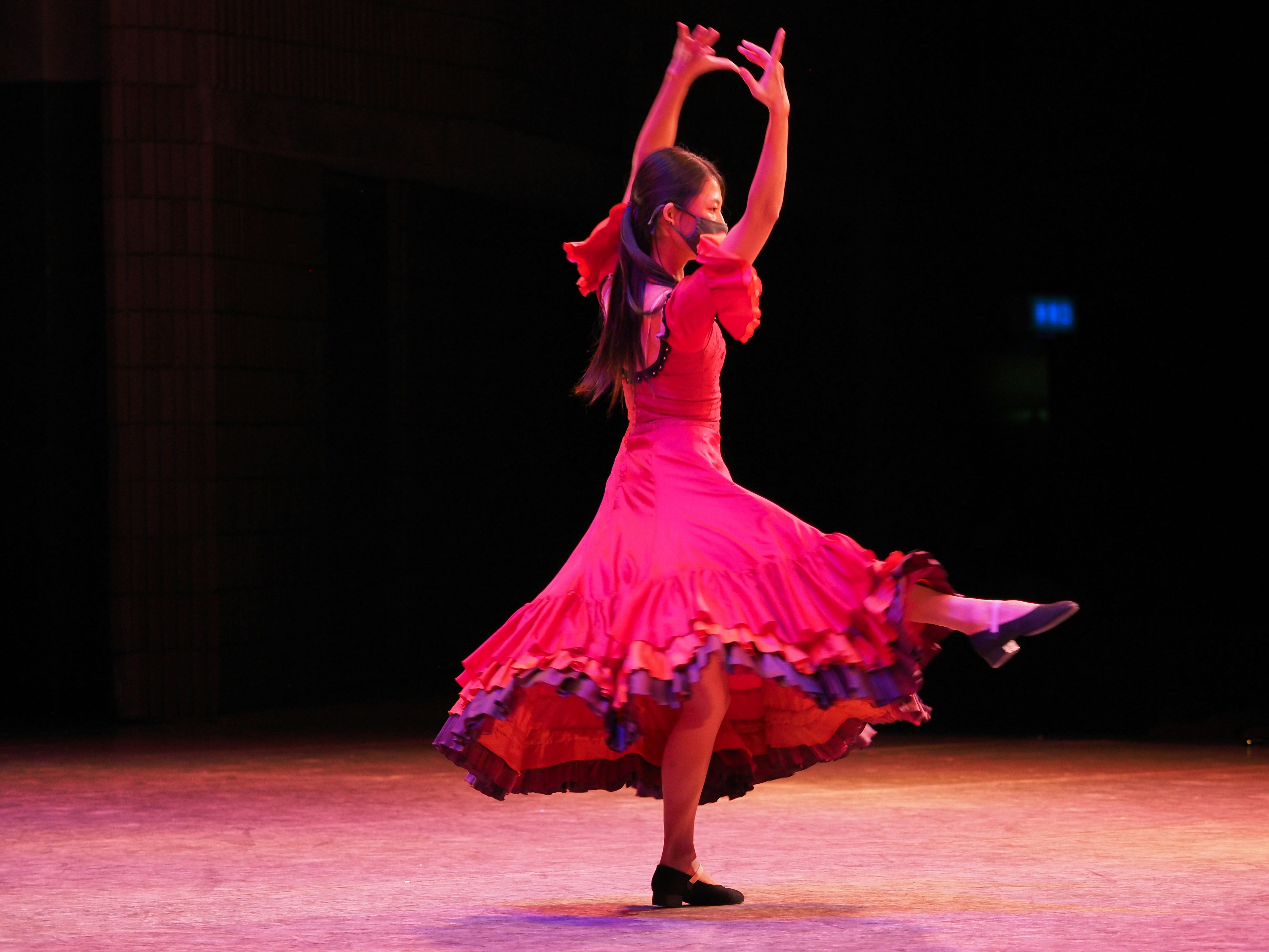 Mukamana Jolie in pink dress dancing energetically on stage