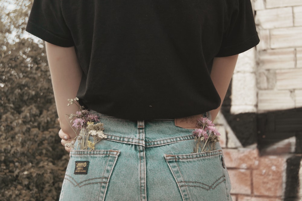 a person wearing a pair of jeans with flowers in their pockets
