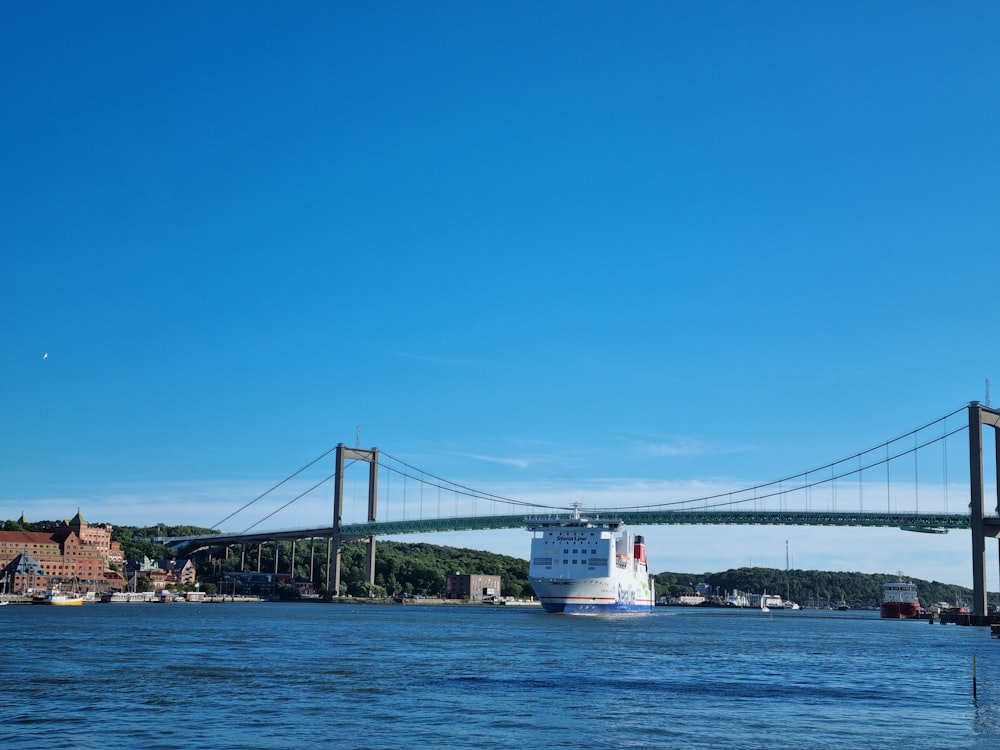 a cruise ship passing under a bridge on a clear day