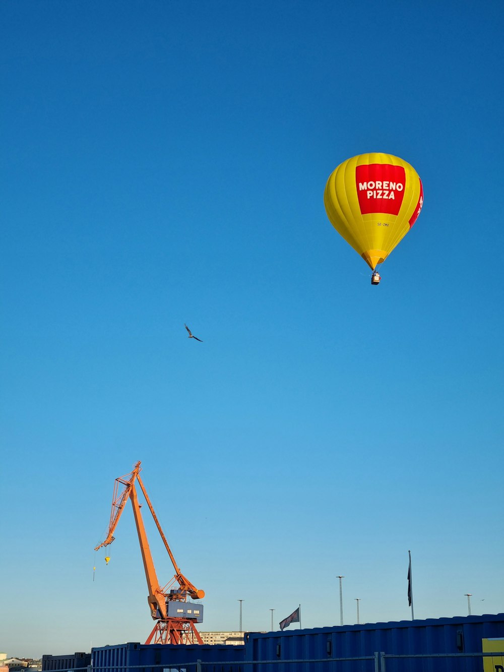 a yellow and red hot air balloon flying over a building