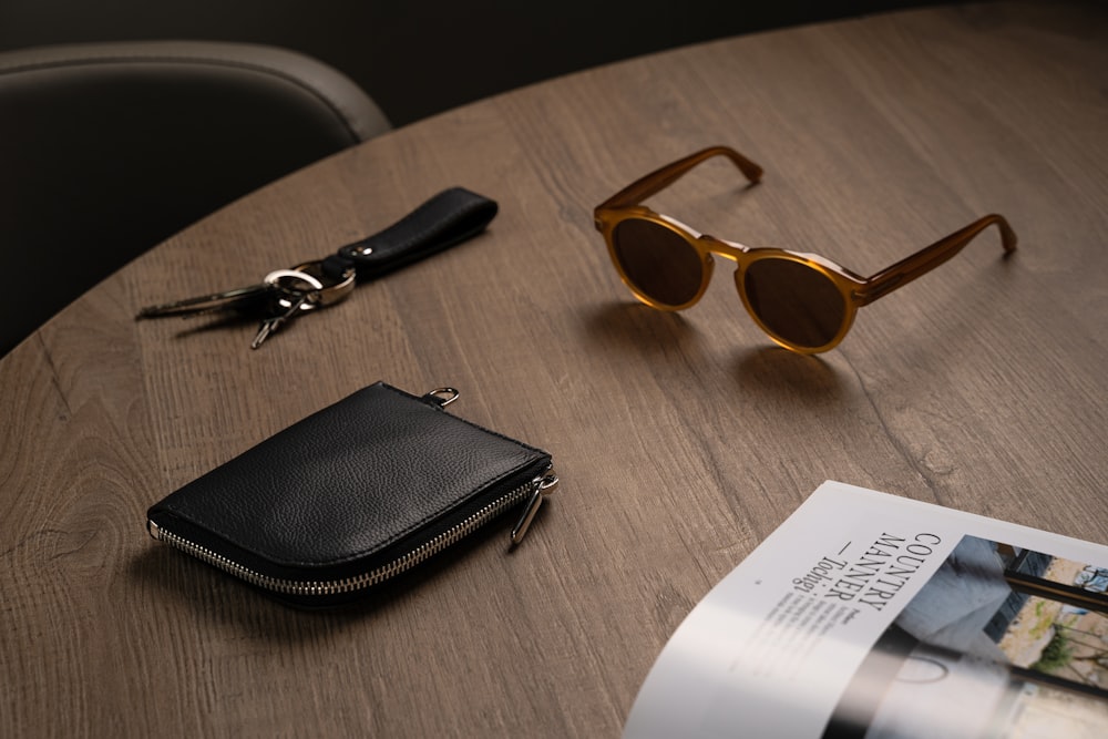 a wooden table topped with a wallet and sunglasses