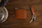 Collection of leather wallets and keychains arranged neatly on a rustic wooden background