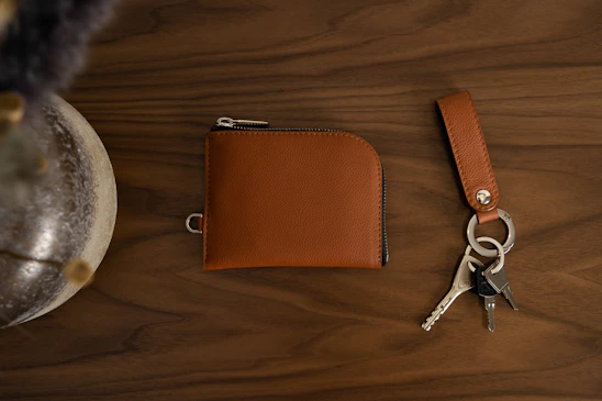 Close-up of a sleek leather key pouch resting on a wooden table with soft natural light.