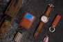 a watch, wallet, and other items laid out on a table