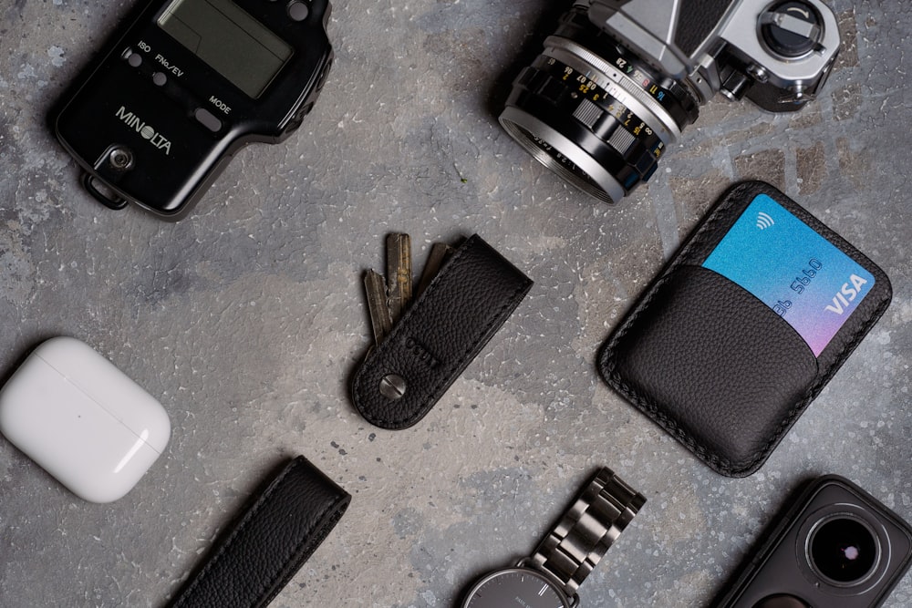 a camera, wallet, keys, and other items laid out on a table