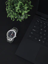 A close-up of a sleek, minimalistic workspace with a laptop, a plant, and soft natural light.