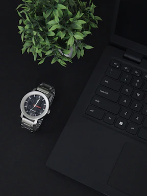 A close-up of a sleek, minimalistic workspace with a laptop, a plant, and soft natural light.