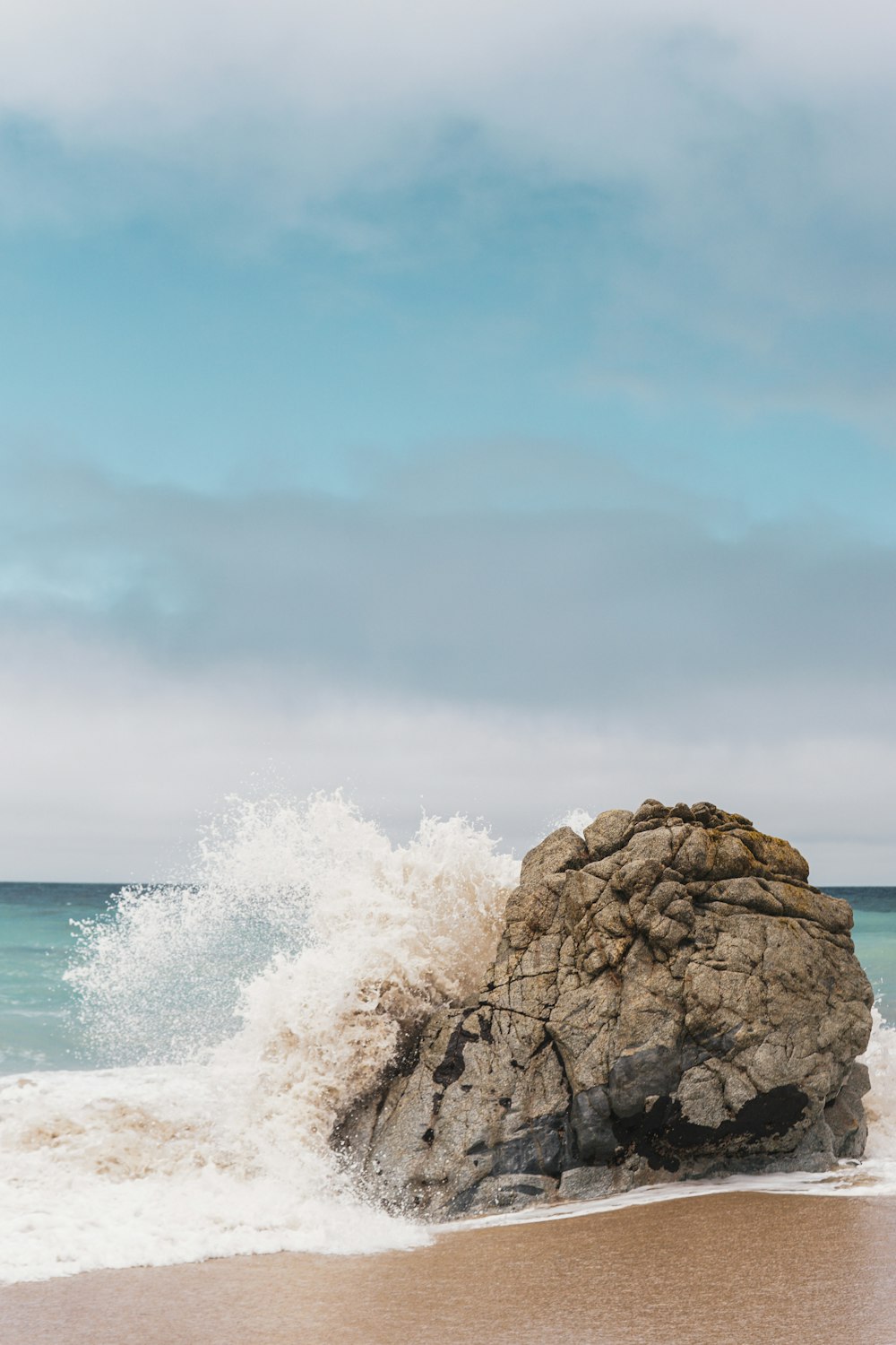 a large rock sitting on top of a sandy beach