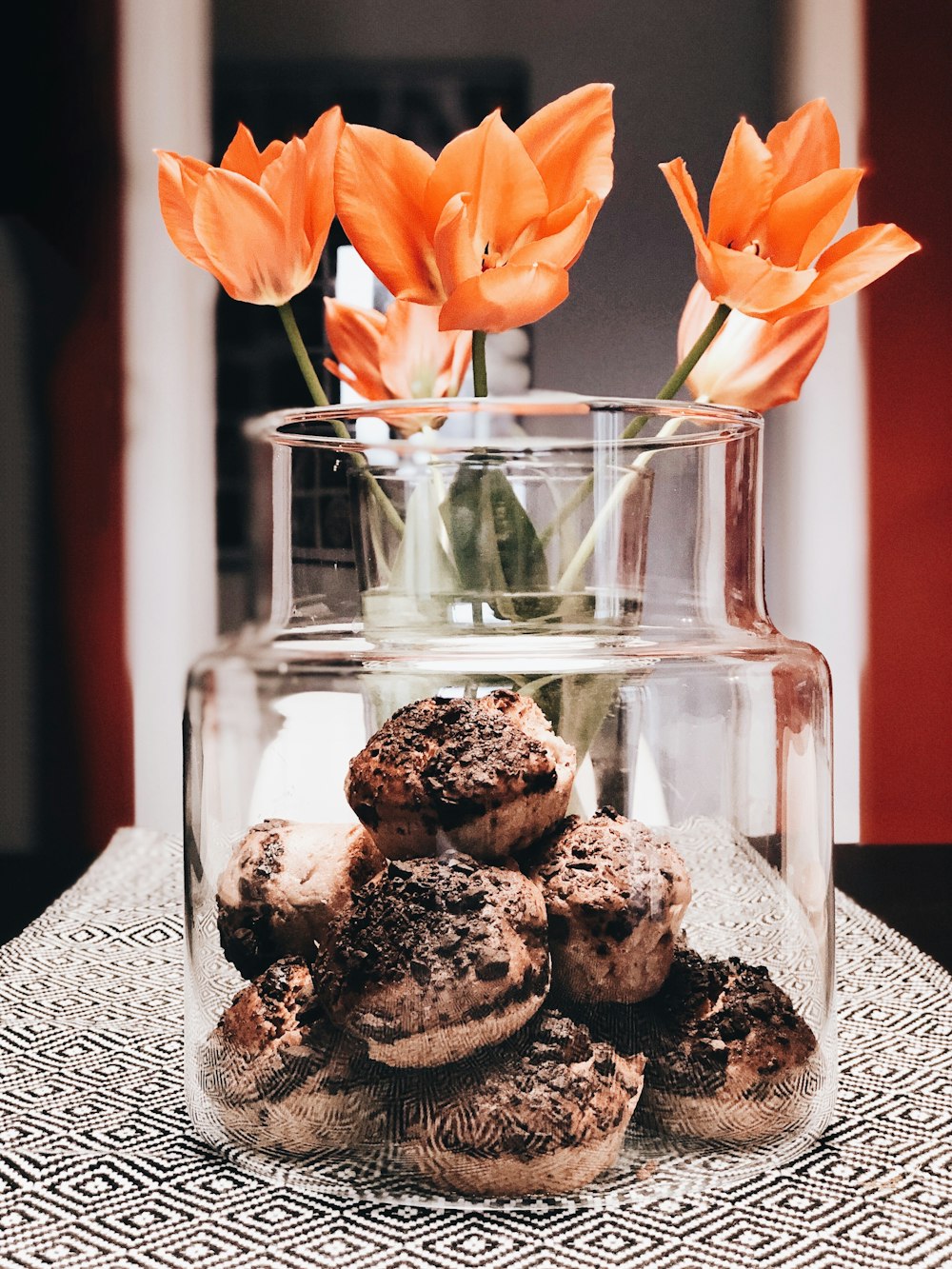 a glass vase filled with muffins and orange flowers