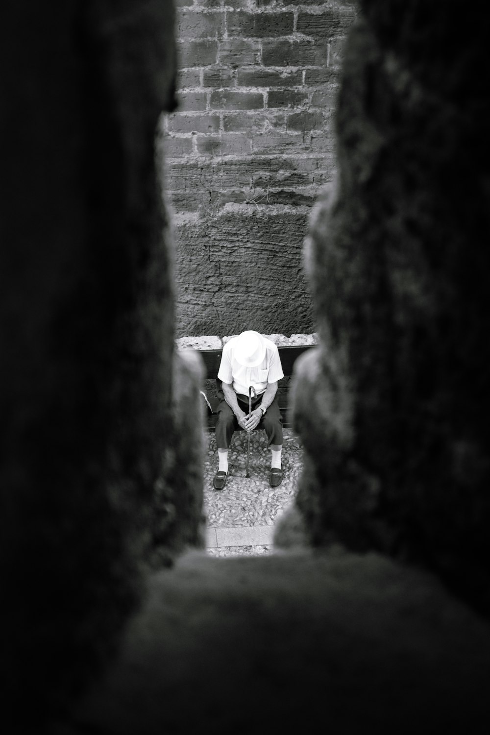 a man sitting on a bench in the middle of a brick wall