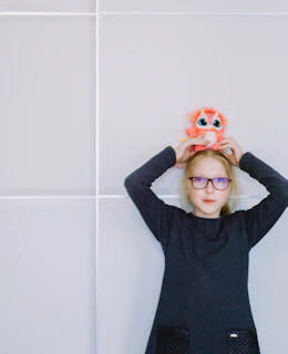 Young person holding a colorful, handmade product with button details