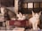 Two cats are resting on top of stacked books, with a focus on one cat lying on a red book titled 'Evidence.' The background includes a gridded window and a beige chair.