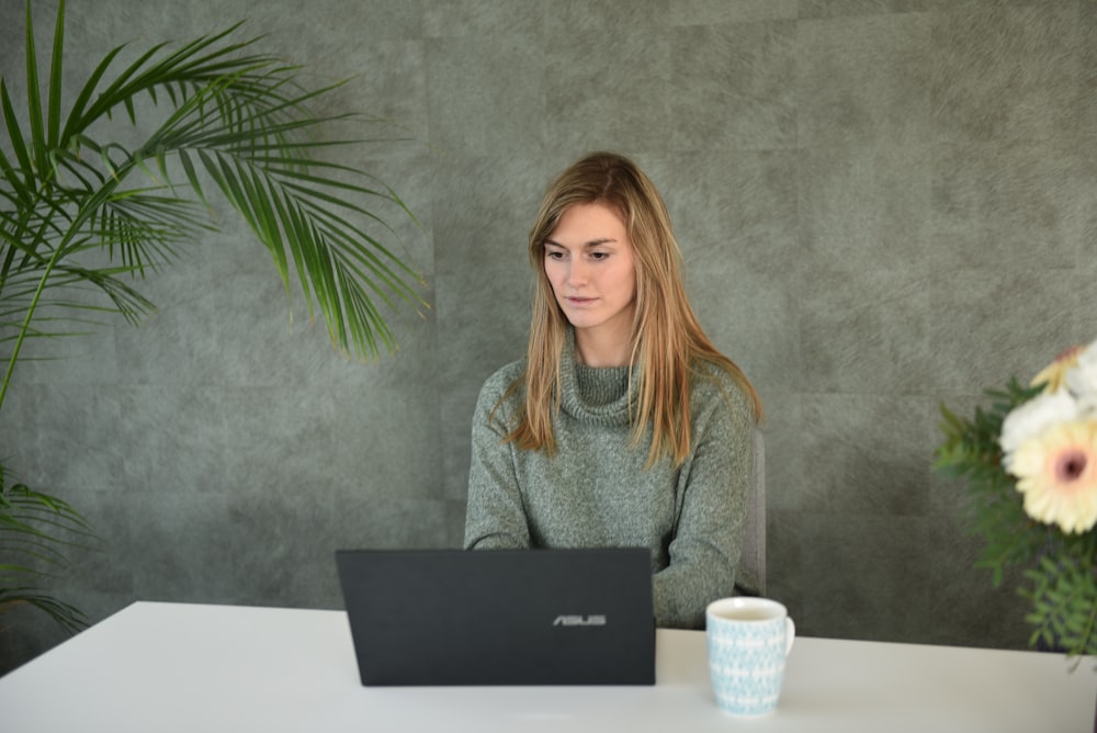 a woman sitting at a table with a laptop