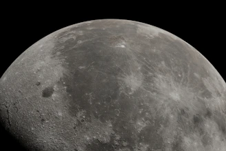 Close-up of a sharp lunar crater with Mars glowing vividly in the background under cinematic lighting.