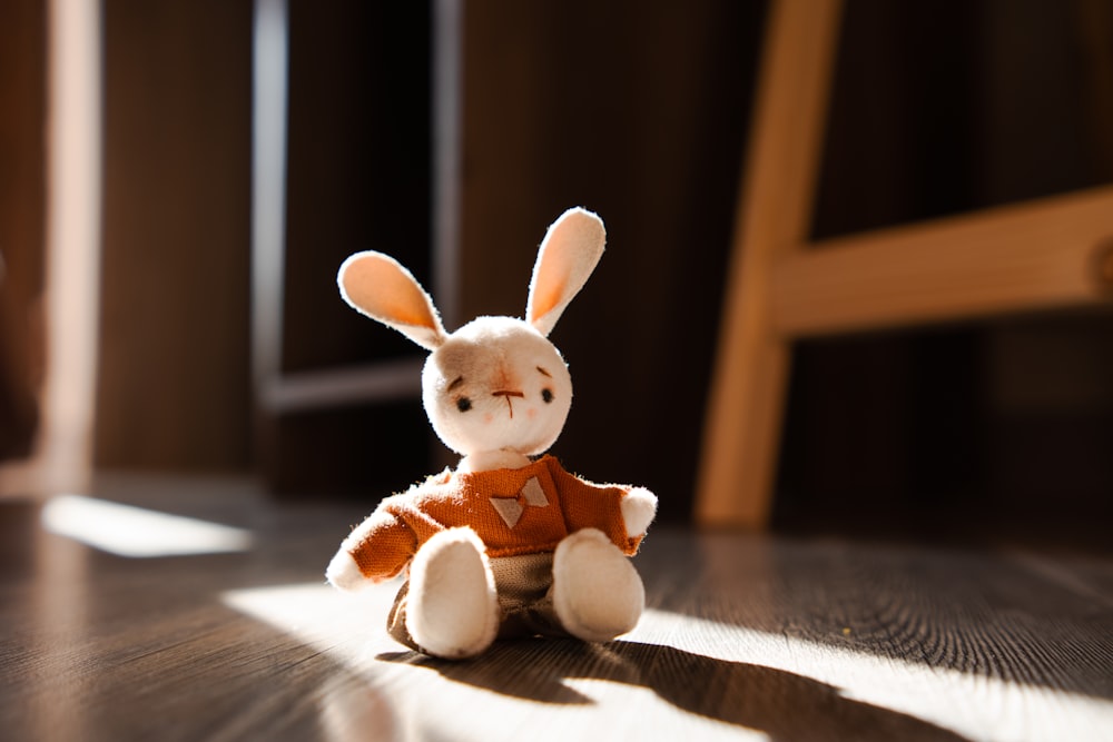 a small stuffed rabbit sitting on a wooden floor
