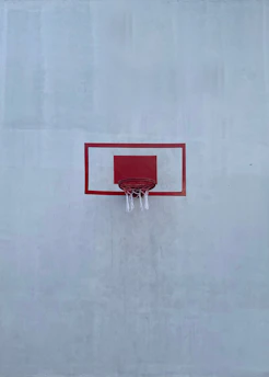 a basketball hoop with a red backboard on a white wall