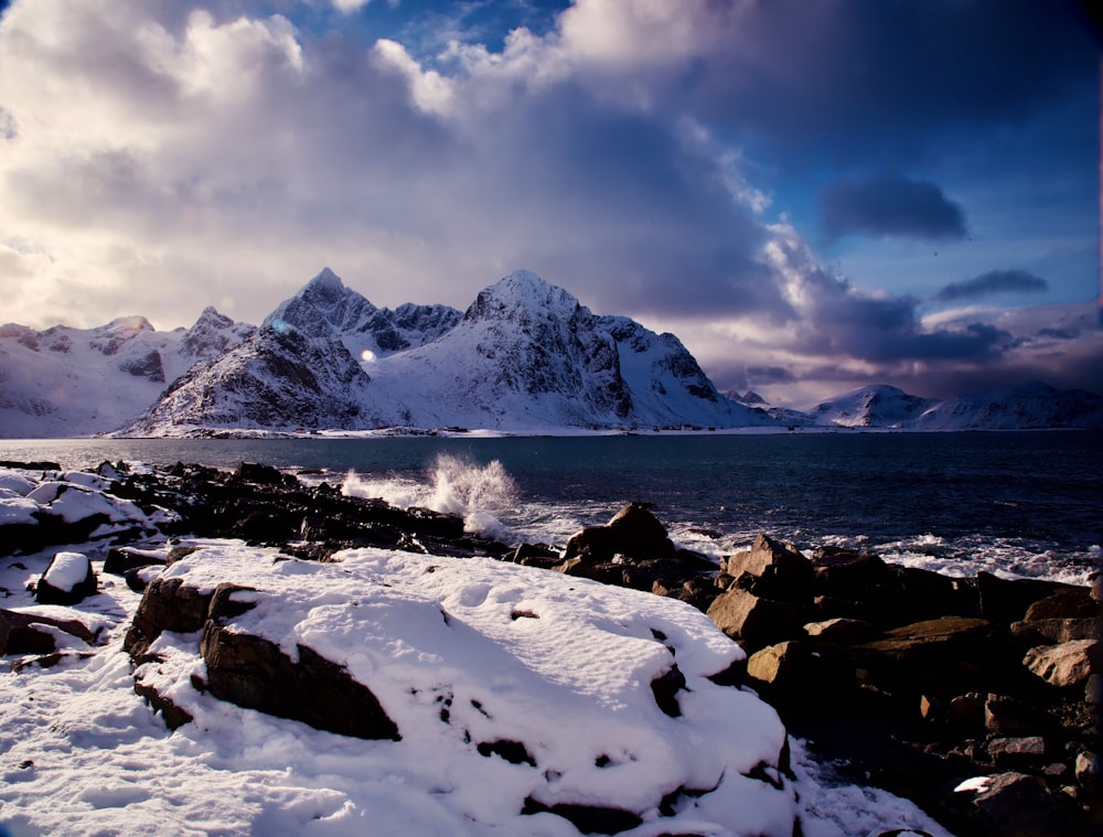 a rocky shore covered in snow under a cloudy sky