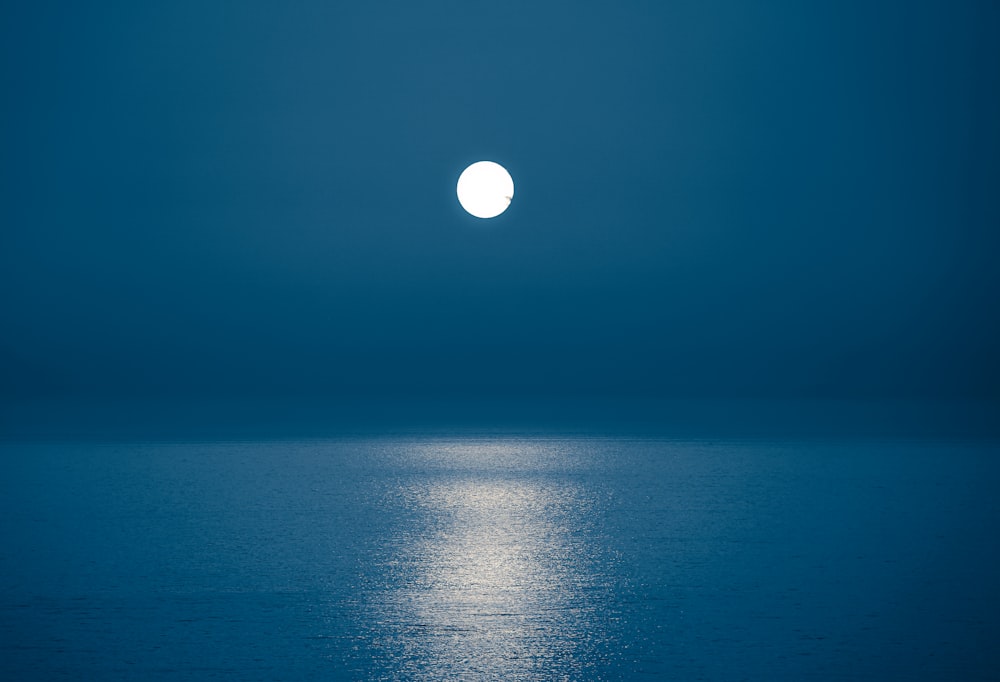 a full moon is seen over the ocean