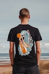 a man standing on a beach wearing a t - shirt with an image of a