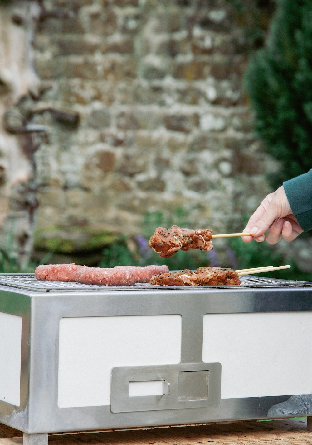 a person holding a skewer of food over a grill