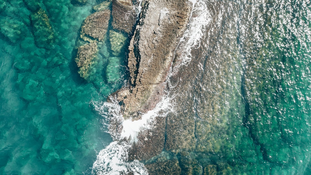 an aerial view of the ocean and rocks