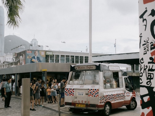 The s.l.i.m sanford van parked in a lively neighborhood with families gathered around for ice cream.