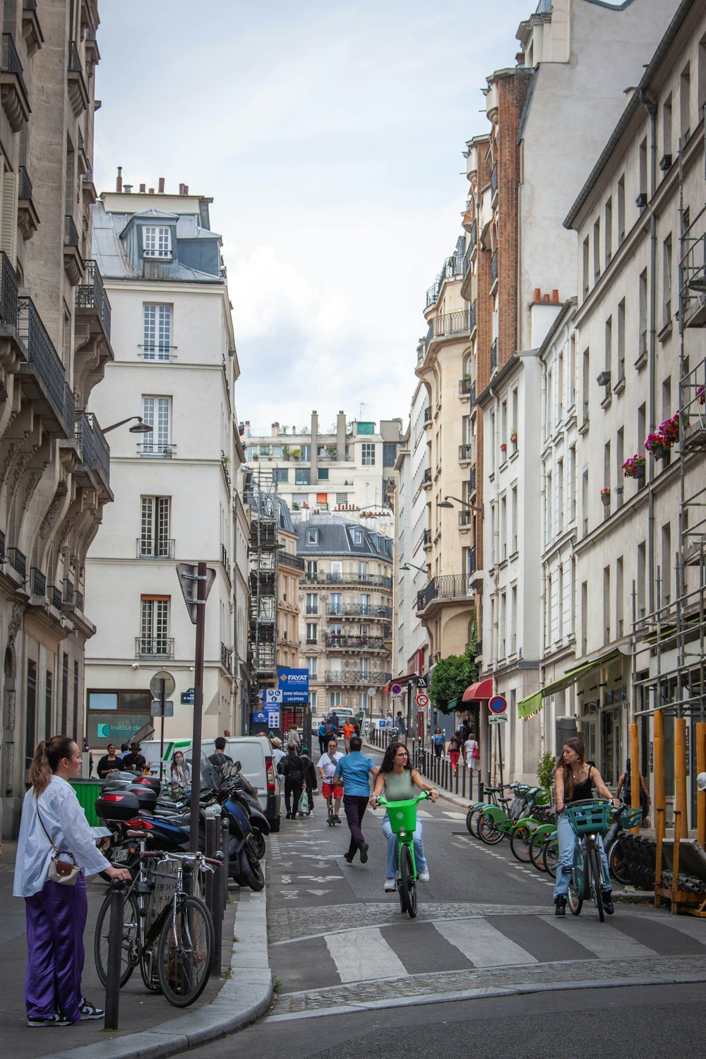 a group of people walking down a street next to tall buildings