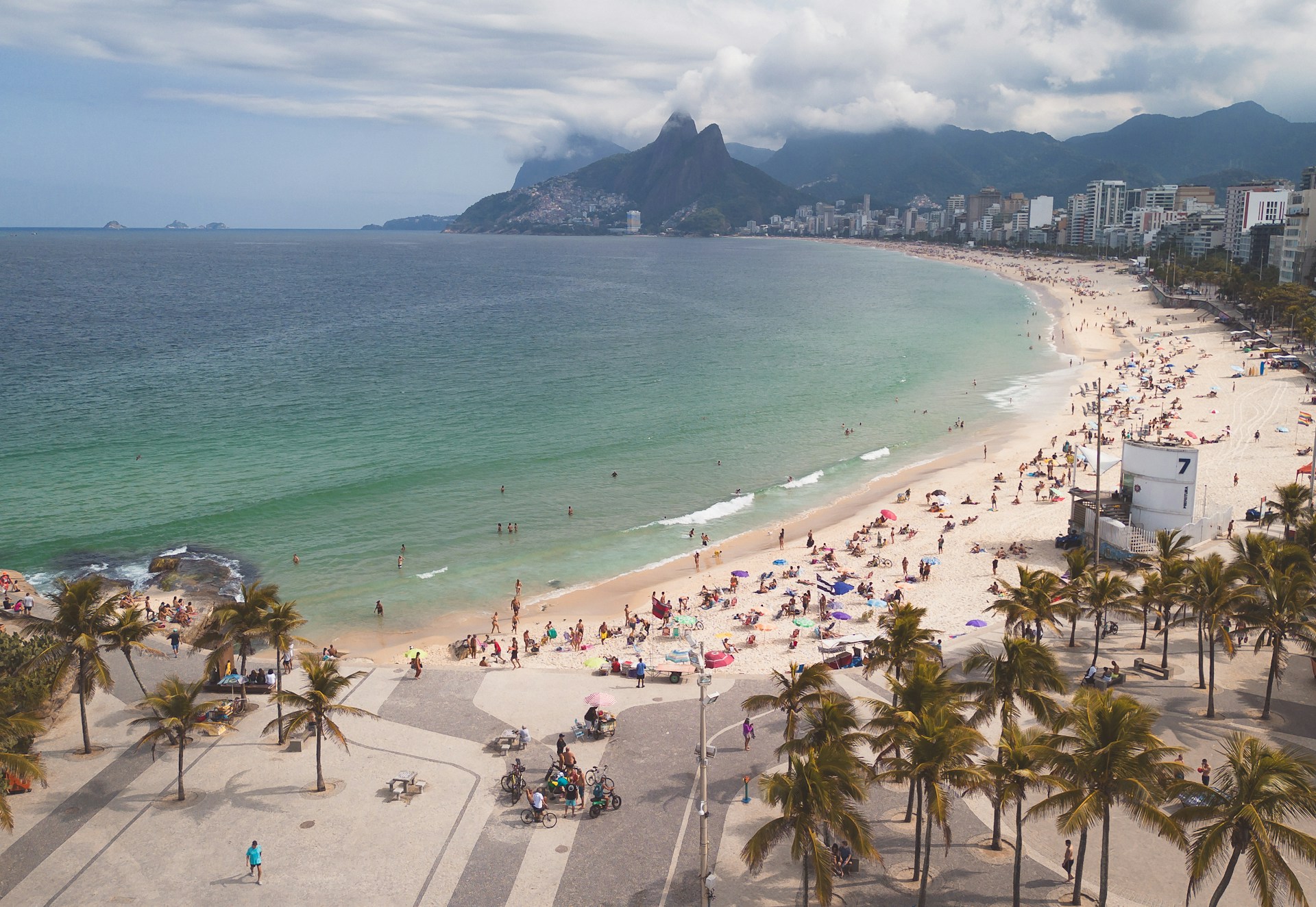 a crowded beach with a mountain in the background