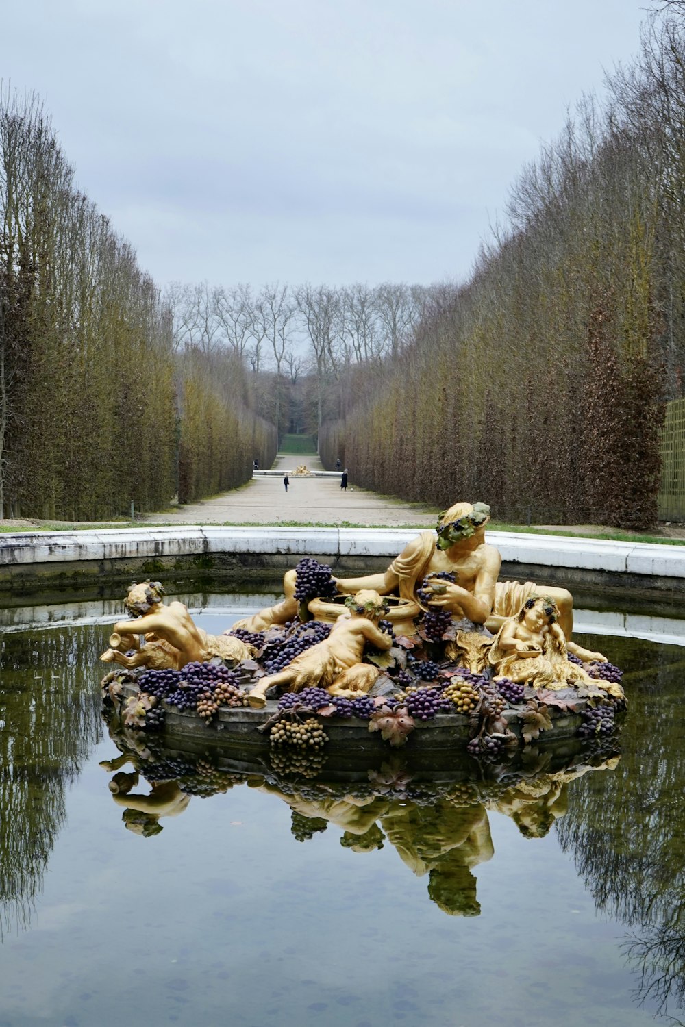 a sculpture in the middle of a pond surrounded by trees